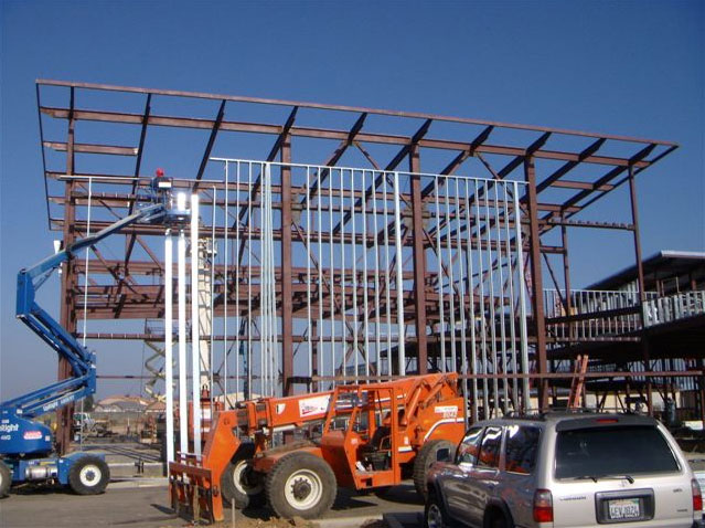 A steel structure is being built, with a person on a lifter working on the structure